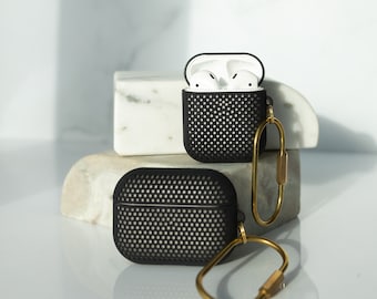 Peut inclure: Étui noir pour Airpods avec un porte-clés doré. L'étui a un design texturé en nid d'abeille.