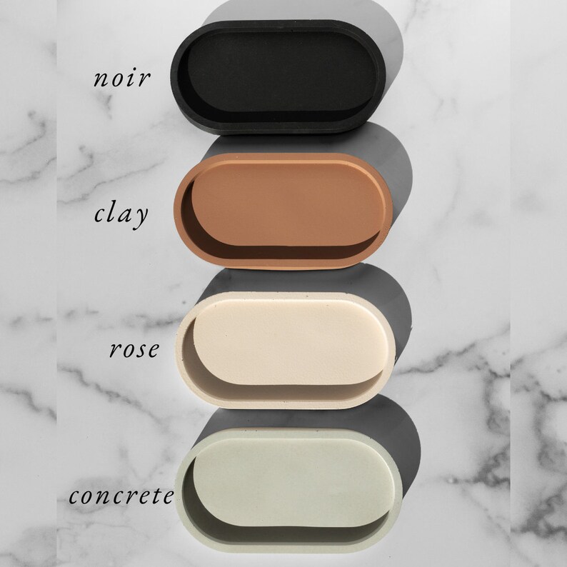 Peut inclure: Quatre plateaux ovales de diff&eacute;rentes couleurs&nbsp;: noir, marron, beige et gris clair. Les plateaux sont empil&eacute;s les uns sur les autres, le plateau noir en haut et le plateau gris clair en bas. Les plateaux sont &eacute;tiquet&eacute;s "noir", "argile", "rose" et "b&eacute;ton".