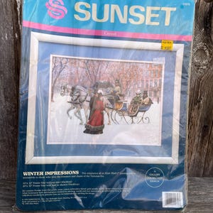 May include: A Sunset crewel embroidery kit titled "Winter Impressions." The kit features a framed image of a horse-drawn carriage in a snowy scene. The kit includes a 10" x 12" frame size without mat (40x30cm) and a 20" x 16" frame size with mat (50x40cm).