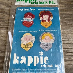 May include: A vintage Kappie Originals Ltd. door knob cover kit. The kit includes patterns for clown, gourmet, baby sleep, and bath time designs. The package is sealed in plastic and features colorful illustrations.
