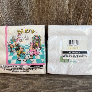 May include: Two packages of paper napkins. One package features Mickey and Minnie Mouse with a jukebox and the word "PARTY". The other package is white with a label that reads "16 BEVERAGE NAPKINS" and measures 9 x 9 inches.