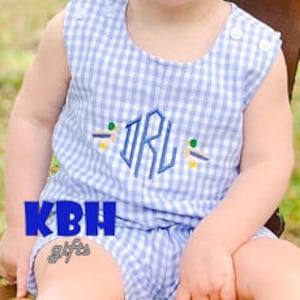 May include: A blue and white gingham sleeveless romper with a monogram and embroidered ducks. The monogram is "IRL" in blue thread.
