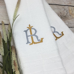 May include: Two white towels with embroidered gold and gray initials "RL" on each towel.