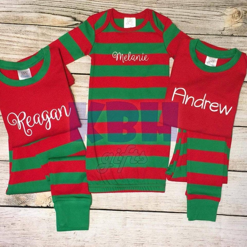 May include: Three sets of red and green striped pajamas with personalized names: Reagan, Melanie, and Andrew.