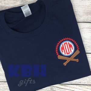 Op de afbeelding: Een donkerblauw t-shirt met een wit en rood baseball-monogram met de tekst "MOM" in een cirkel met gekruiste honkbalknuppels. Het shirt heeft de tekst "KBH gifts" op de voorkant.