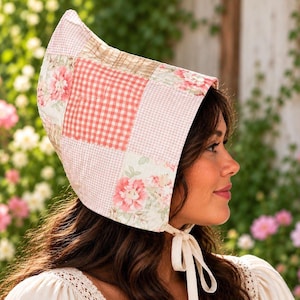 May include: A bonnet featuring a patchwork design with alternating squares of pink and white gingham, floral patterns, and solid light pink fabric. The headwear has a wide, structured brim and is secured under the chin with thin, light-colored fabric ties.