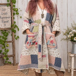May include: A long-sleeved, knee-length patchwork duster coat featuring a quilted texture, a tie-waist belt, and two front pockets. The fabric displays a mix of floral, polka dot, and striped patterns in muted tones, with graphic prints of women on scooters.