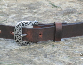 May include: A brown leather belt with a silver buckle featuring a decorative floral design.