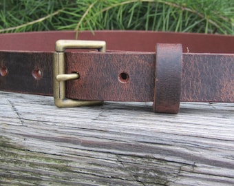 May include: A brown leather belt with a brass buckle. The belt has a distressed look and is made of thick, durable leather.