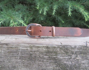 May include: A brown leather belt with a copper-toned buckle. The belt is distressed and has a rustic look.