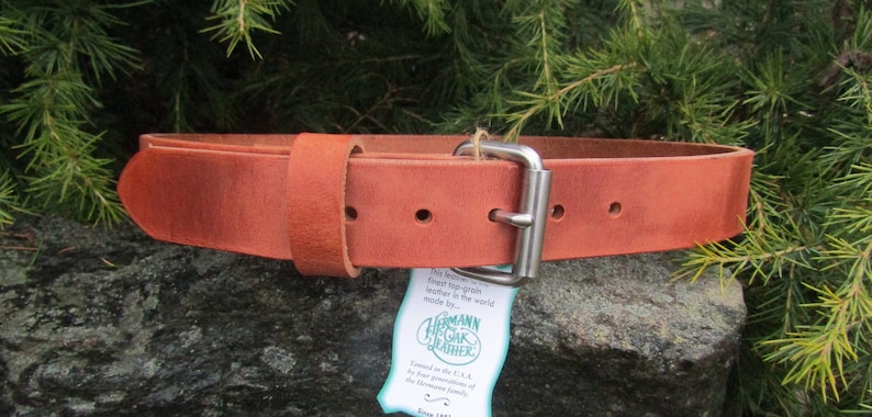 K&ouml;nnte beinhalten: Ein brauner Lederg&uuml;rtel mit einer silbernen Schnalle. Der G&uuml;rtel ist aus Vollleder und wird von Hermann Oak Leather hergestellt.