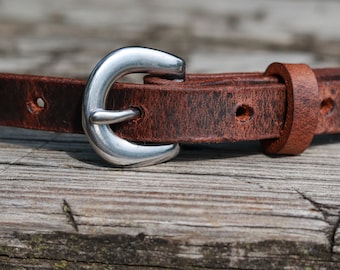 May include: A brown leather belt with a silver buckle. The belt is distressed and has a worn look.