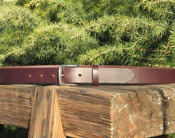 May include: A brown leather belt with a silver buckle. The belt is lying on a wooden surface.