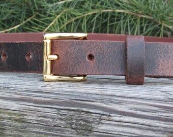 May include: A brown leather belt with a gold buckle. The belt has a distressed look and is made of high-quality leather.