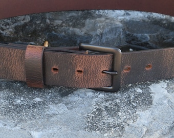 May include: A brown leather belt with a black metal buckle. The belt has a distressed look and is made of a thick, durable leather.