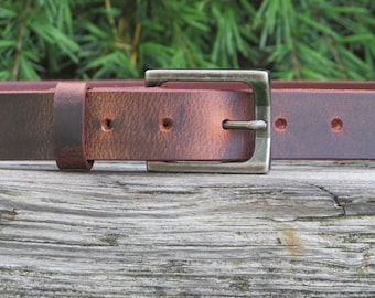 May include: A brown leather belt with a silver buckle. The belt is distressed and has a worn look.