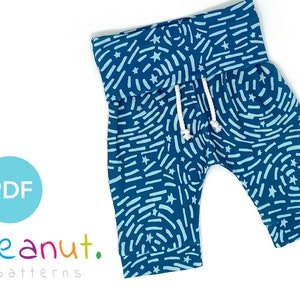 May include: A teal blue pair of children's pants with a white drawstring and a light blue and white abstract pattern. The pants have a folded waistband and a small blue label with the text "Peanut Patterns" on the right leg.