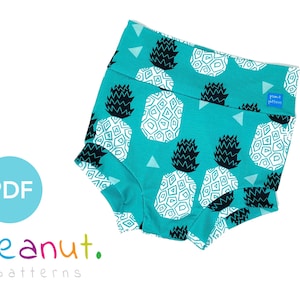 May include: A teal blue fabric baby bloomer with a white and black pineapple print. The bloomer has a wide elastic waistband and a ruffled leg opening. The fabric has a small blue label with the text "peanut patterns".