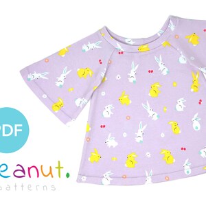 May include: A purple t-shirt with a bunny and egg pattern. The t-shirt has a round neckline and bell sleeves. The text "PDF" and "peanut. patterns" is visible in the image.