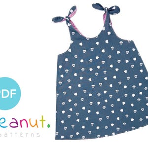 May include: A blue sleeveless dress with white crown print and pink tie straps. The dress has a round neckline and a gathered skirt. The text "peanut. patterns" is printed below the image.
