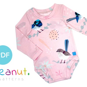 Könnte beinhalten: Ein rosa langärmliger Baby-Strampler mit einem bunten Aufdruck von Vögeln und Blumen. Der Strampler hat einen runden Ausschnitt und lange Ärmel. Der Druck ist in den Farben Blau, Grün und Weiß gehalten. Der Strampler trägt den Text "peanut. patterns" am unteren Rand.