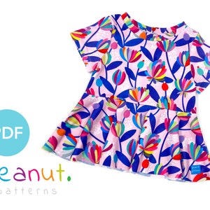 May include: A pink, blue, and multi-colored floral print short-sleeved top with a ruffled hem. The top is made by Peanut Patterns.