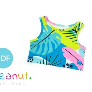 May include: A sleeveless tank top with a tropical print featuring green, blue, pink, and black leaves and dots. The tank top has a white label with the text "Peanut Patterns".