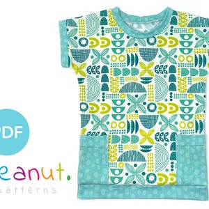 May include: A turquoise and white short-sleeved t-shirt with a geometric pattern in shades of green and yellow. The shirt has two patch pockets on the front.