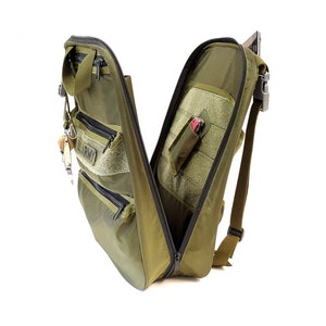May include: A green tactical backpack with multiple pockets and compartments. The backpack is open and the interior is visible. The backpack has a zippered pocket on the front and a small pocket on the side. The backpack has a strap on the top and a strap on the side.