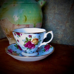 May include: A floral teacup and saucer set with a blue and white floral pattern. The teacup has a gold rim and a handle. The saucer has a matching floral pattern.