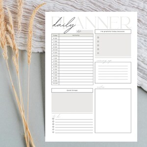 Puede incluir: Un planificador diario blanco con un diseño minimalista. El planificador incluye secciones para la hora, la actividad y las notas, con las palabras "daily" y "planner" mostradas. También tiene secciones para "I'm grateful today because", "coming up" y "to do".