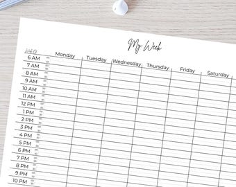 Może przedstawiać: Biały tygodniowy planer z tytułem "My Week" w kursywie. Planer ma kolumny dla każdego dnia i przedziały czasowe od 6:00 do 22:00. Pióro, okulary i słuchawki znajdują się na drewnianej powierzchni.
