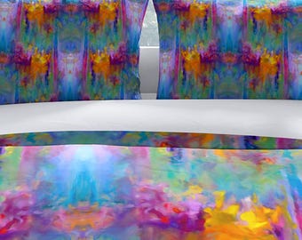 Puede incluir: Una cama con un colorido juego de cama abstracto. El juego incluye una funda nórdica y dos fundas de almohada con un diseño vibrante en tonos de azul, morado, naranja y amarillo. La cama está frente a una ventana.
