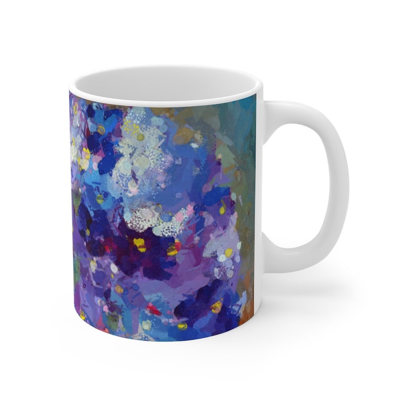 Pu&ograve; includere: Tazza in ceramica bianca con un design astratto colorato in tonalit&agrave; di viola, blu e giallo. Il design ricorda un gruppo di fiori.
