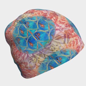 May include: A colourful beanie with a blue, red and yellow geometric pattern. The pattern features a repeating design of circles and lines.