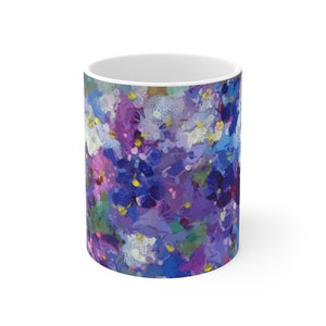Pu&ograve; includere: Tazza in ceramica bianca con un motivo floreale astratto in viola, blu e bianco. Il motivo ricorda le pennellate.