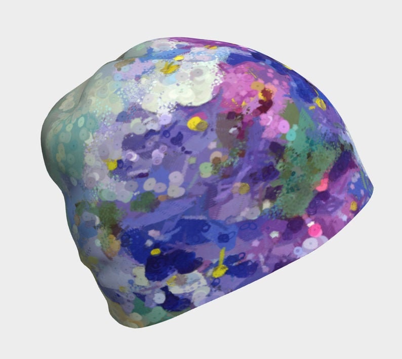 Pu&ograve; includere: Un berretto viola, blu, verde e giallo con un design astratto di schizzi di vernice.