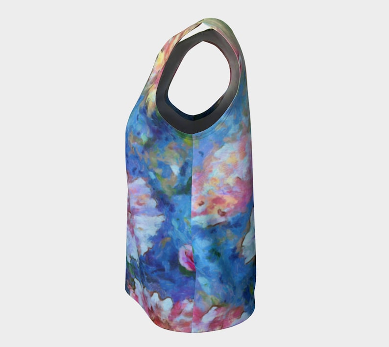 May include: A sleeveless tank top with a colorful floral print on a blue background. The print features pink, white, and yellow flowers.