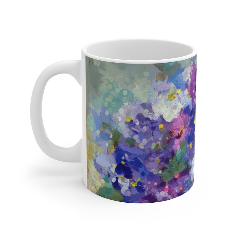 Pu&ograve; includere: Tazza in ceramica bianca con un design floreale astratto colorato in tonalit&agrave; di viola, blu e bianco. Il design ricorda un mazzo di fiori.