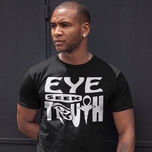 May include: Black t-shirt with a white graphic design that says "EYE SEEK TRUTH" with an Egyptian eye symbol.