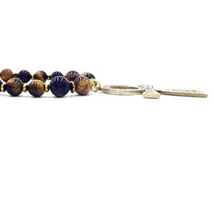 May include: A gold Ankh pendant necklace with a brown and gold tiger's eye bead chain.