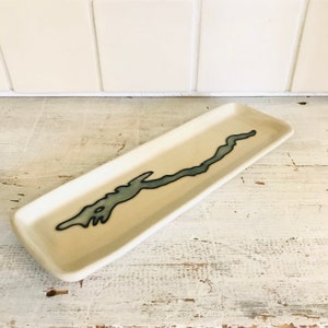 May include: A white ceramic serving tray with a blue outline of a lake or river design.