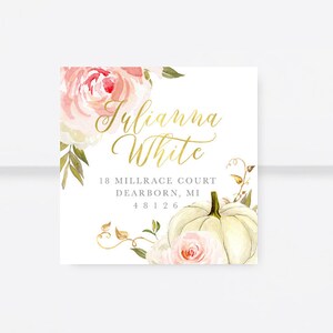 Peut inclure: Une carte blanche avec un motif floral aquarelle composé de roses roses et d'une citrouille blanche. Le texte "Julianna White" est écrit en lettres d'or. L'adresse "18 Millrace Court, Dearborn, MI 48126" est imprimée en gris sous le nom.