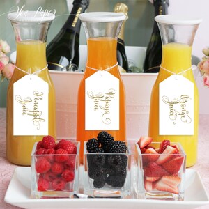 May include: A white serving tray with three glass containers filled with fresh fruit. The containers are labeled with white tags that say "Orange Juice", "Papaya Juice", and "Pineapple Juice".