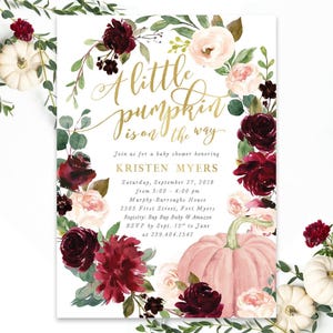 May include: A rectangular baby shower invitation card featuring a floral wreath of deep burgundy and soft pink roses with green leaves. The text reads A little pumpkin is on the way, Kristen Myers, and event details in gold and black ink.