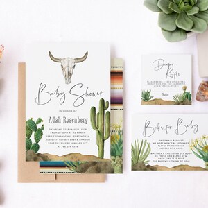 May include: A baby shower invitation set featuring a steer skull illustration, green cacti, and desert landscape graphics. The text includes Baby Shower, Adah Rosenberg, Diaper Raffle, and Books for Baby, alongside event details on a white background.