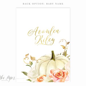 May include: A white pumpkin with a gold inscription that reads "Avonlea Riley" surrounded by white and peach roses and green leaves.