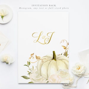 Op de afbeelding: Witte achterkant van een uitnodiging met een gouden monogram "L&J" en een aquarel-illustratie van een witte pompoen met witte bloemen en groen.