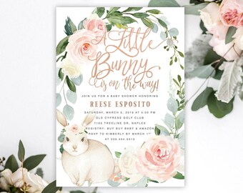 May include: A rectangular baby shower invitation card featuring a watercolor illustration of a light brown bunny wearing a small pink flower crown, surrounded by a wreath of soft pink roses, white flowers, and green eucalyptus leaves.