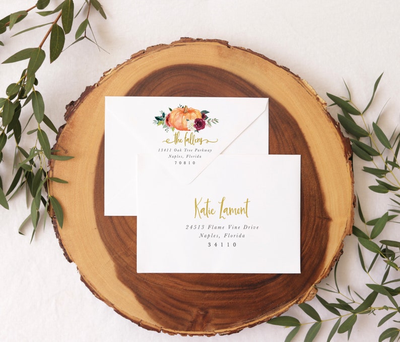 Op de afbeelding: Twee witte enveloppen met gouden letters. De bovenste envelop heeft een aquarel-illustratie van een pompoen, bladeren en bloemen. De tekst op de bovenste envelop luidt "the fallens" en bevat een adres. De onderste envelop heeft de tekst "Katie Lamont" en bevat een adres.